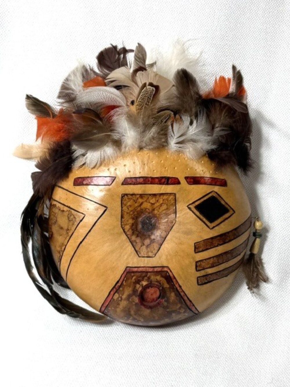 Artisan signed, painted hanging gourd mask w/ multiple kinds of feathers.